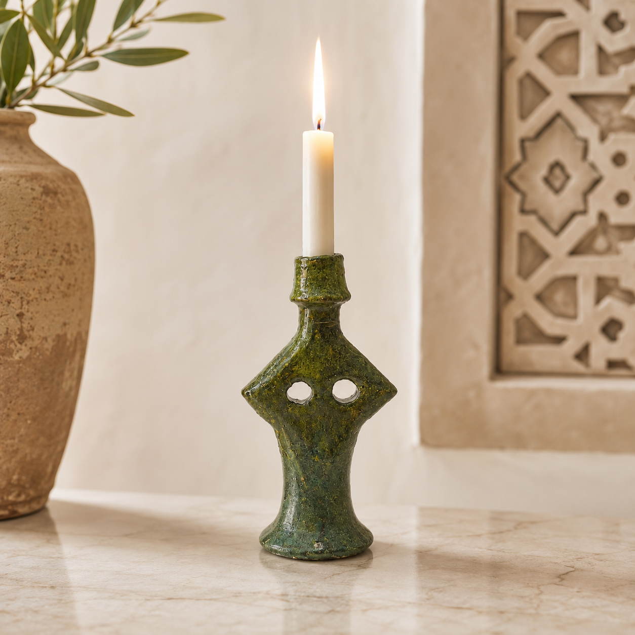 Handmade Moroccan green ceramic candle holder with a lit white candle in a stylish home décor setting.