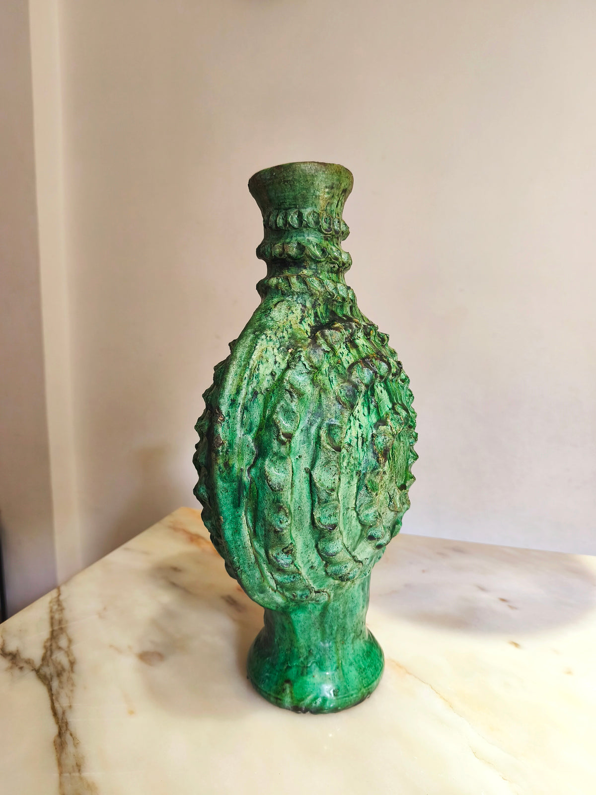 Antique Moroccan green ceramic candle holder, tall textured relief, 50 cm height, on a marble surface.
