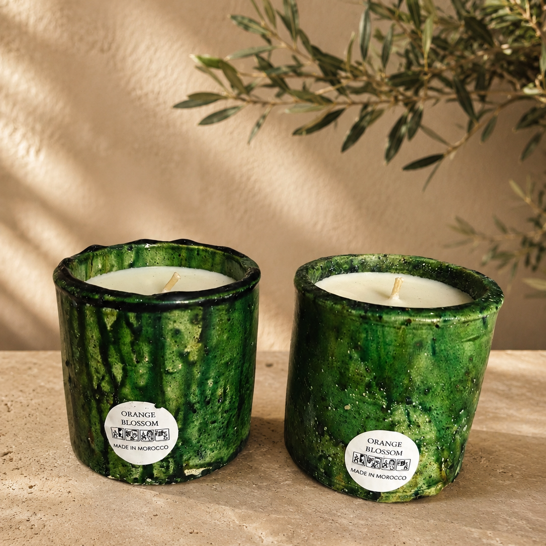 Two artisan hand-poured candles in green textured jars on a clean white background.