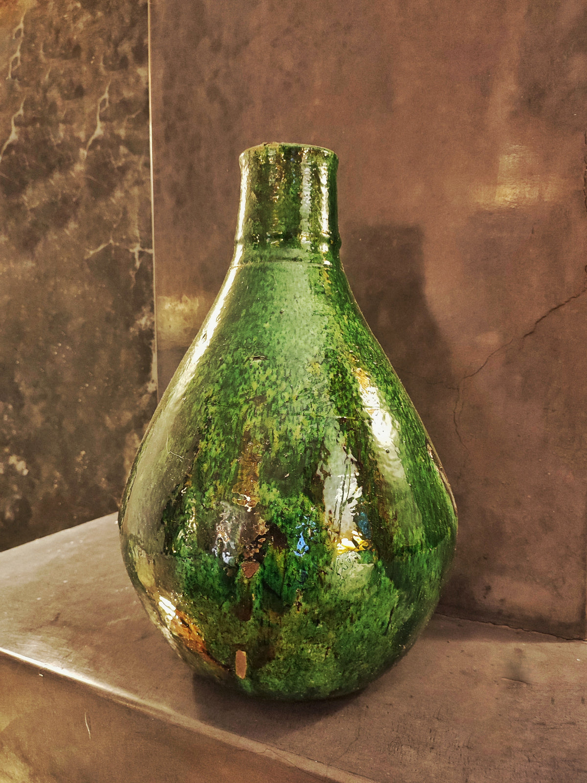 Large green Tamegroute ceramic vase displayed on the top of  chimney, showcasing handmade Moroccan pottery with rustic glaze and artisanal texture