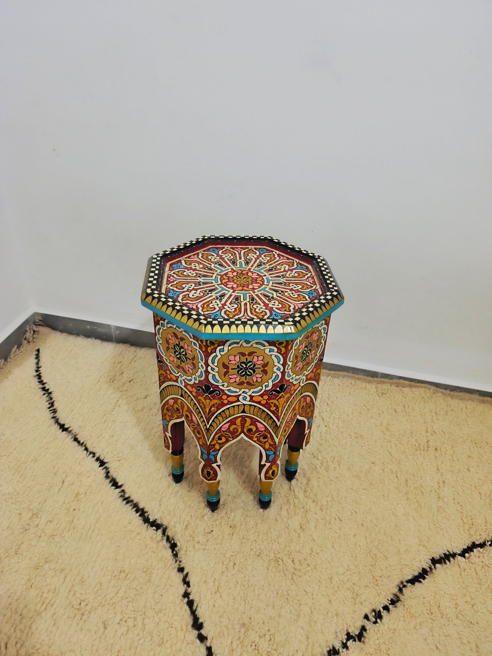 Moroccan hand-printed wooden table with bold Moorish patterns  with beni ourain rug