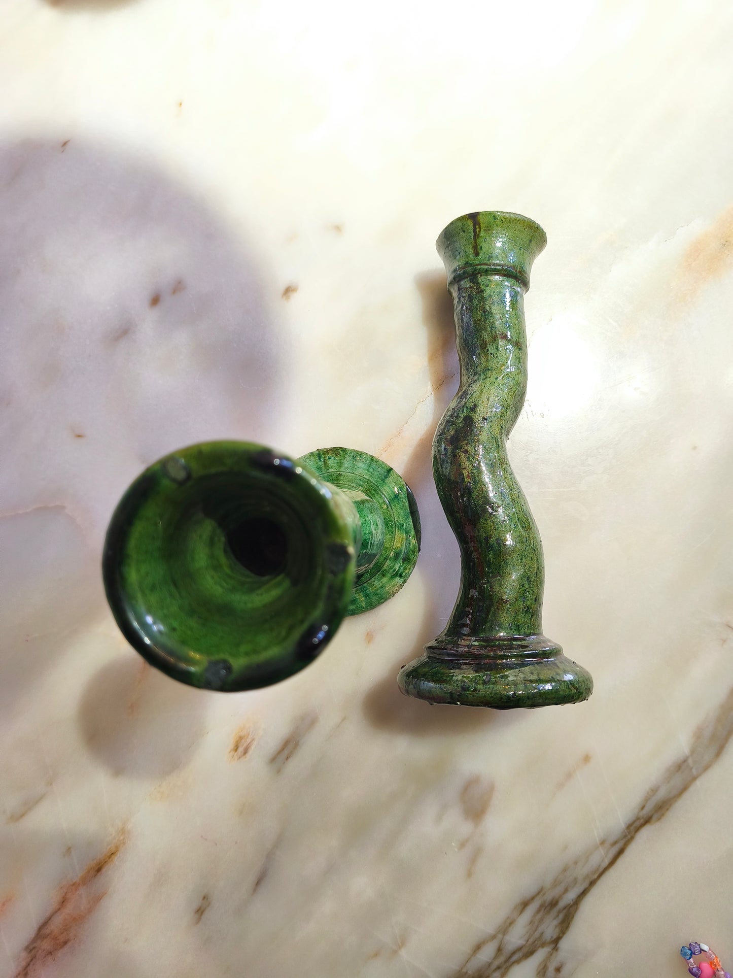 Close-up of handmade Moroccan green ceramic candlestick with glossy glaze and imperfections
